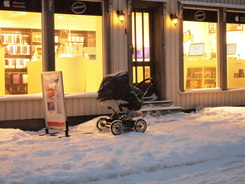 Baby carriage (not empty) left outside of a shop in the snow in Tromsø